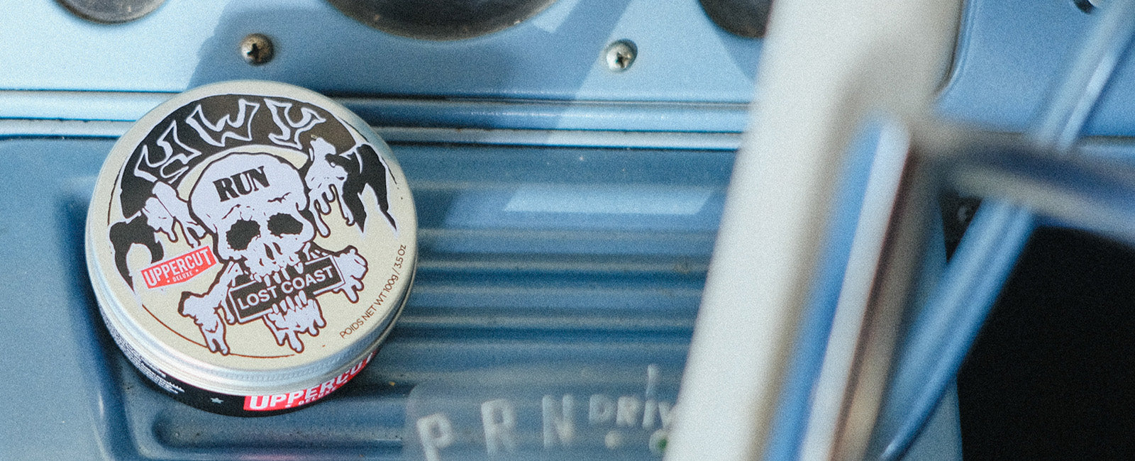 HWY x Uppercut Deluxe Tin sitting on dashboard of car