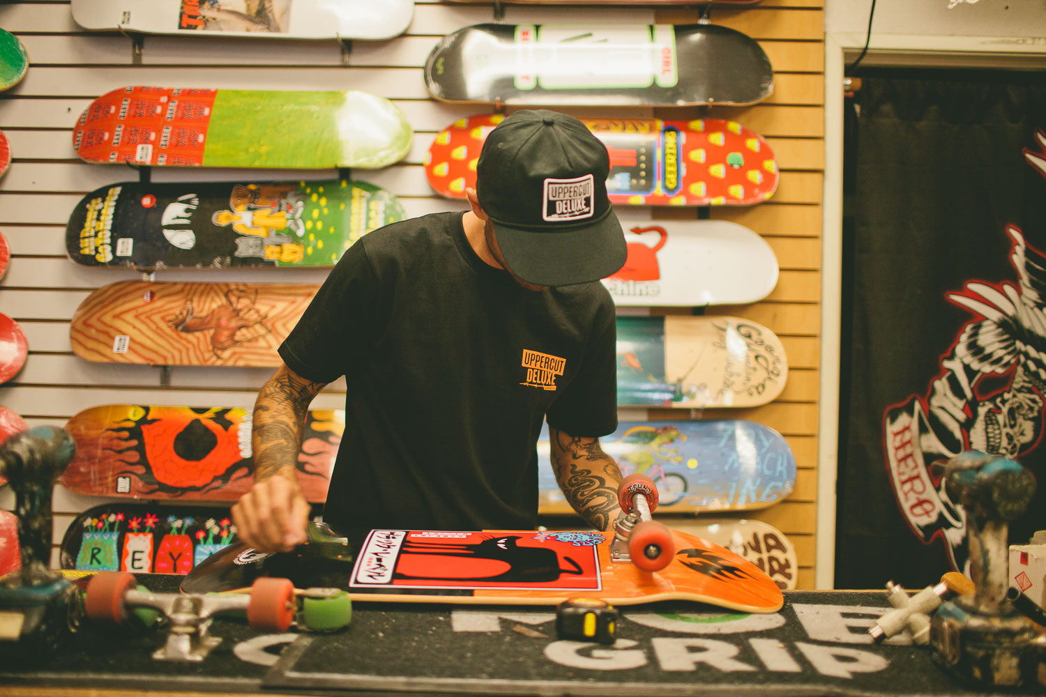 Man working on skateboard wearing Uppercut Deluxe Headliner Hat and Shirt
