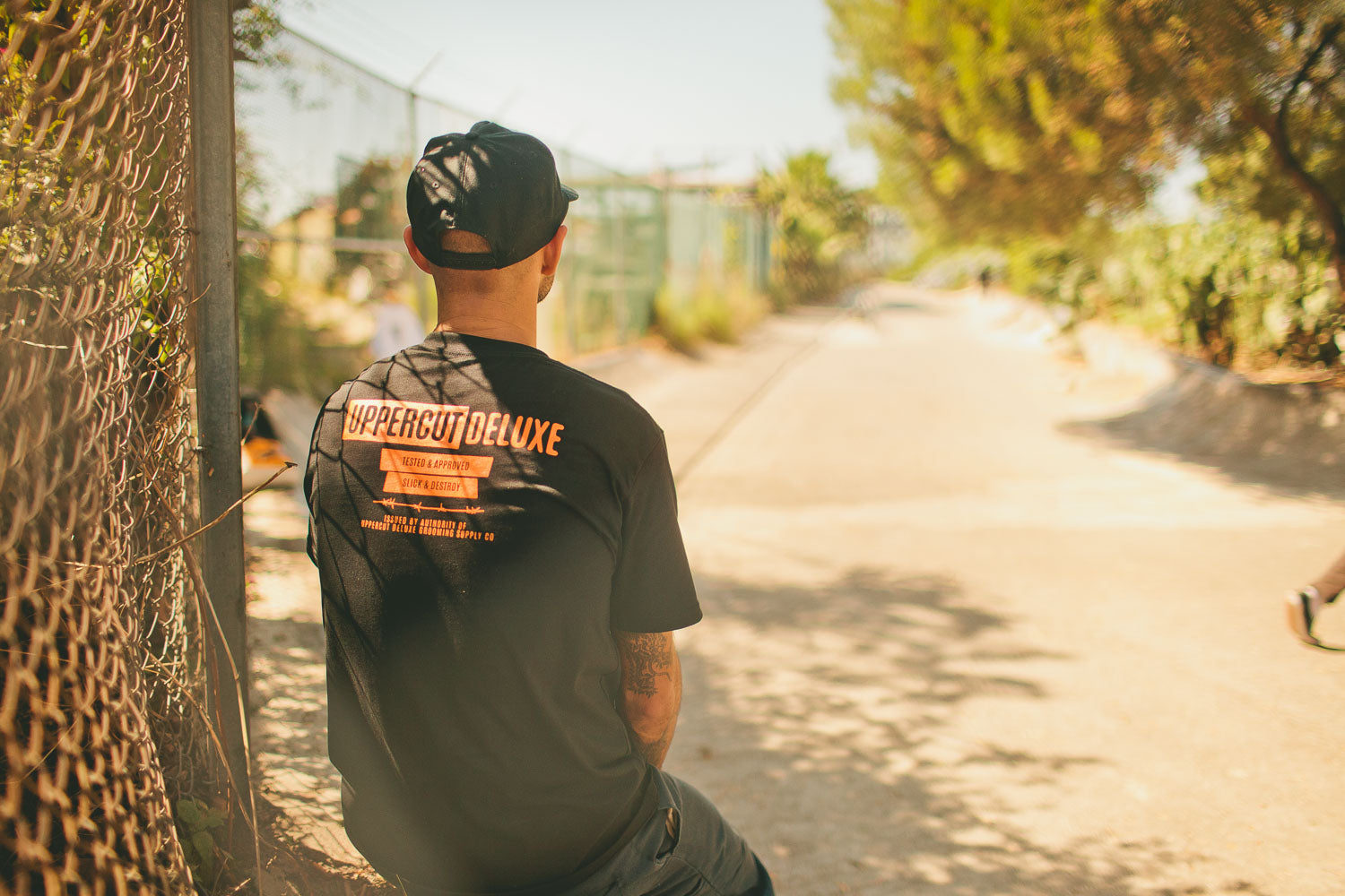 Man sitting down wearing uppercut deluxe headliner shirt and hat